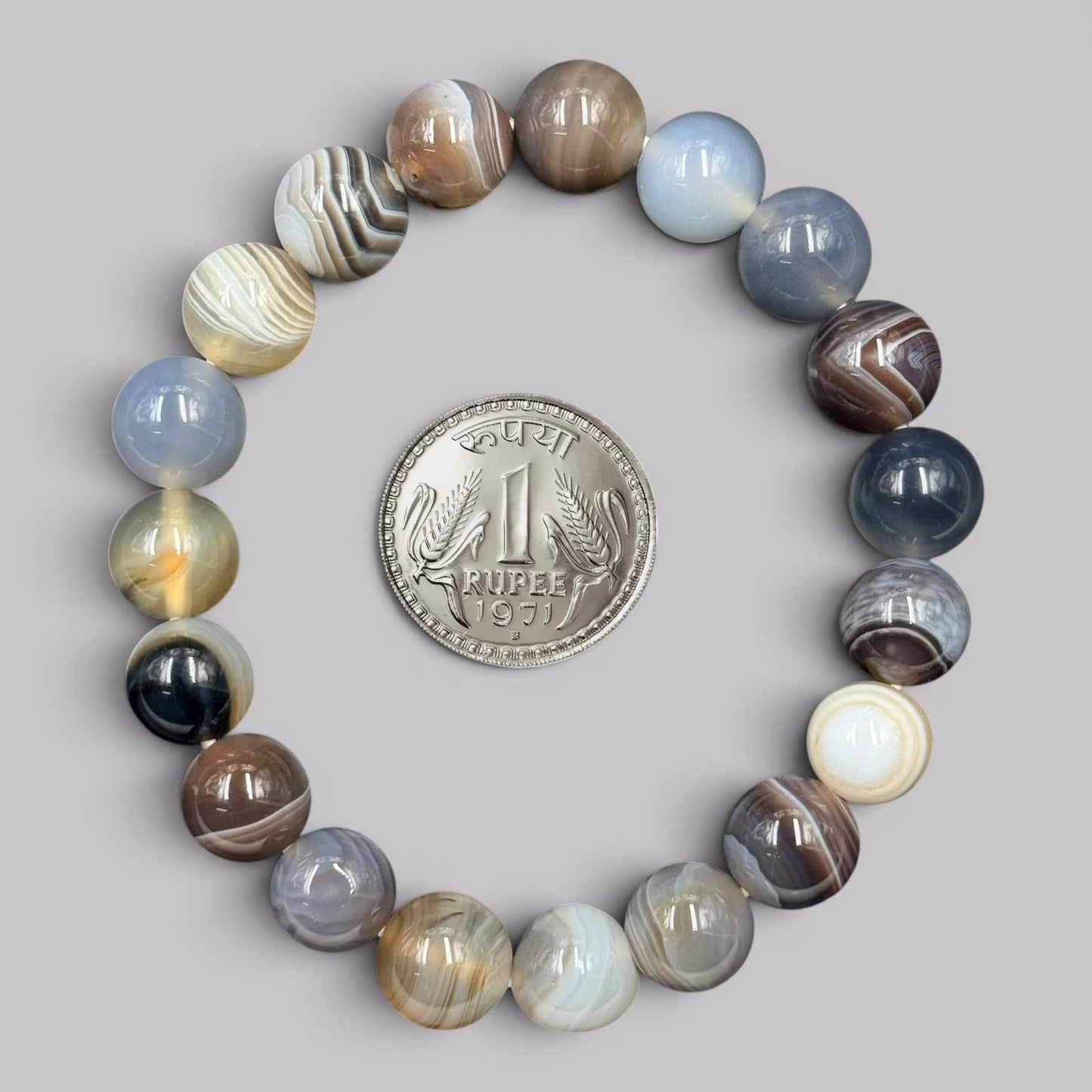 Botswana Agate (Sulemani Hakik) Bracelet with round polished beads in soft earthy tones and a 1971 Indian one rupee coin.
