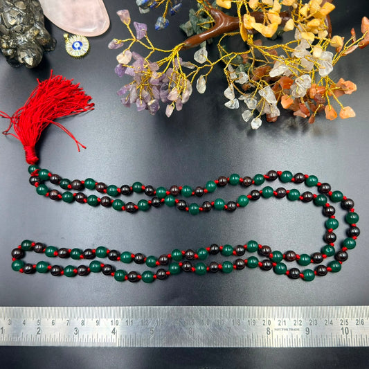 8mm green jade and garnet mala bead necklace with red tassel laid flat next to ruler