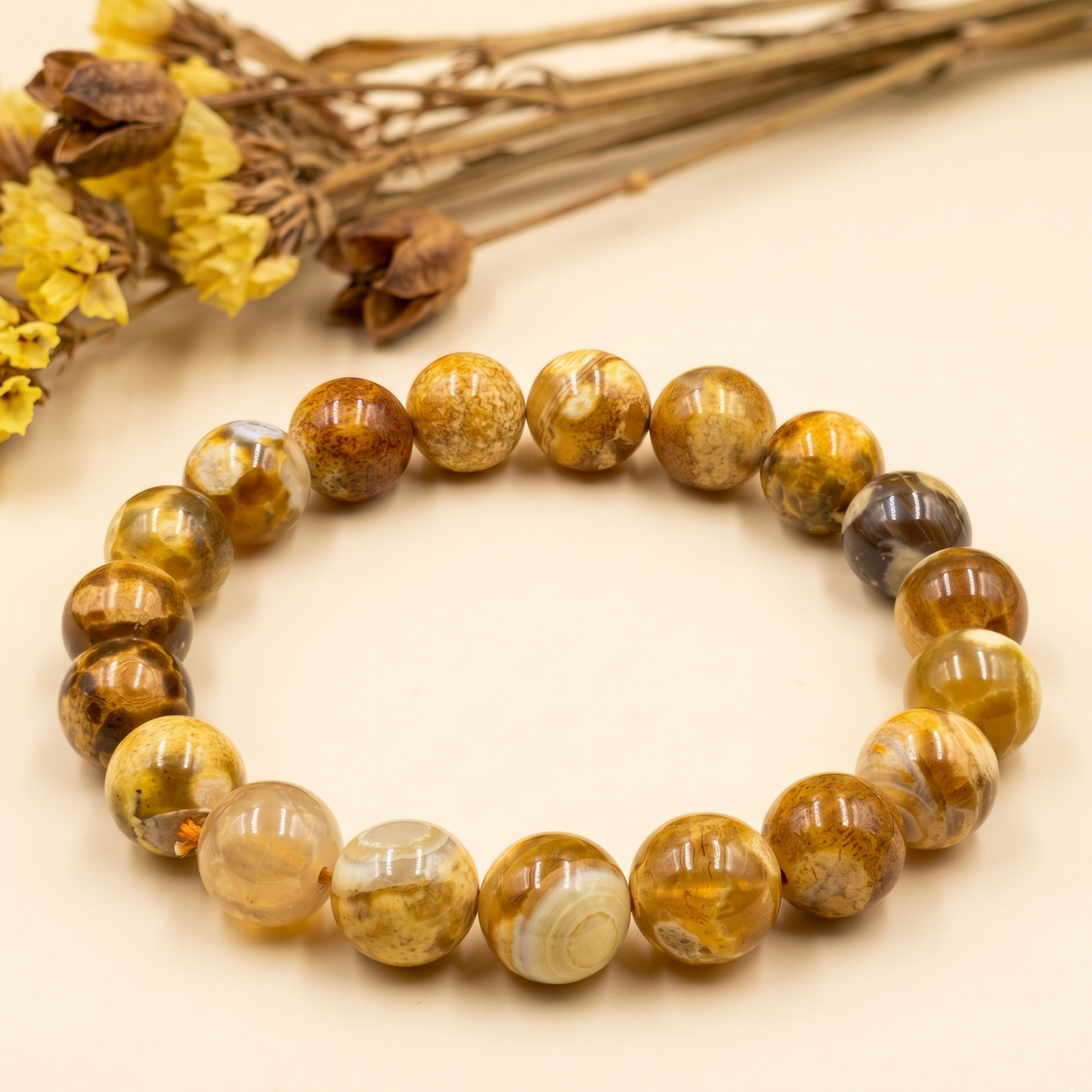 Round polished Fossil Boulder Opal beads bracelet with brown and cream patterns on beige background