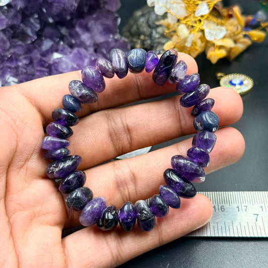 Polished amethyst freeform bracelet shown in hand with ruler background