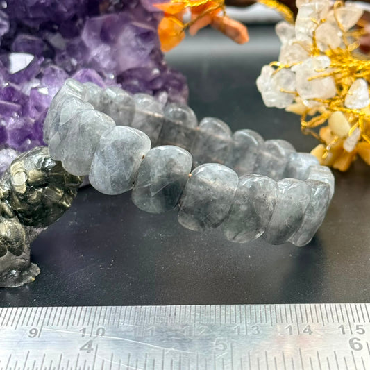 Black cat’s eye flat oval bead bracelet close-up with purple crystals and ruler for size