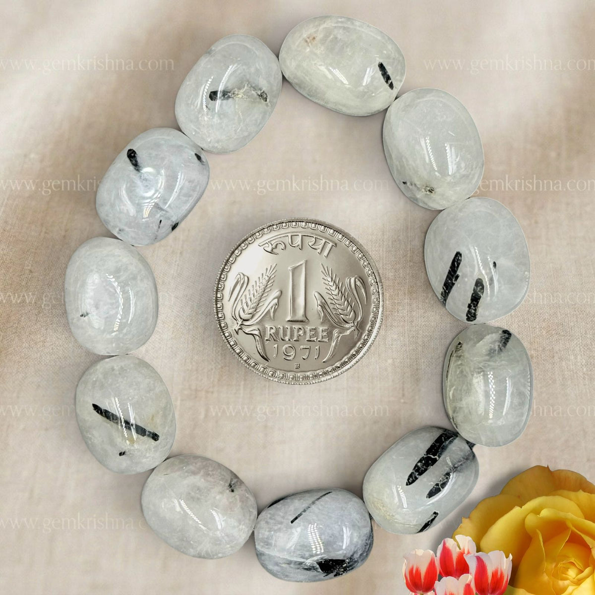 Black rutile quartz tumble bracelet beads with coin for size on beige fabric background