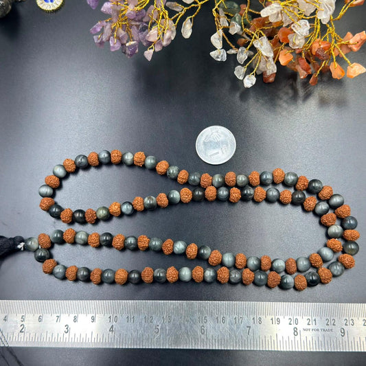 Jaap mala beaded strand close-up on grey surface with blue cat’s eye balls and rudraksha beads