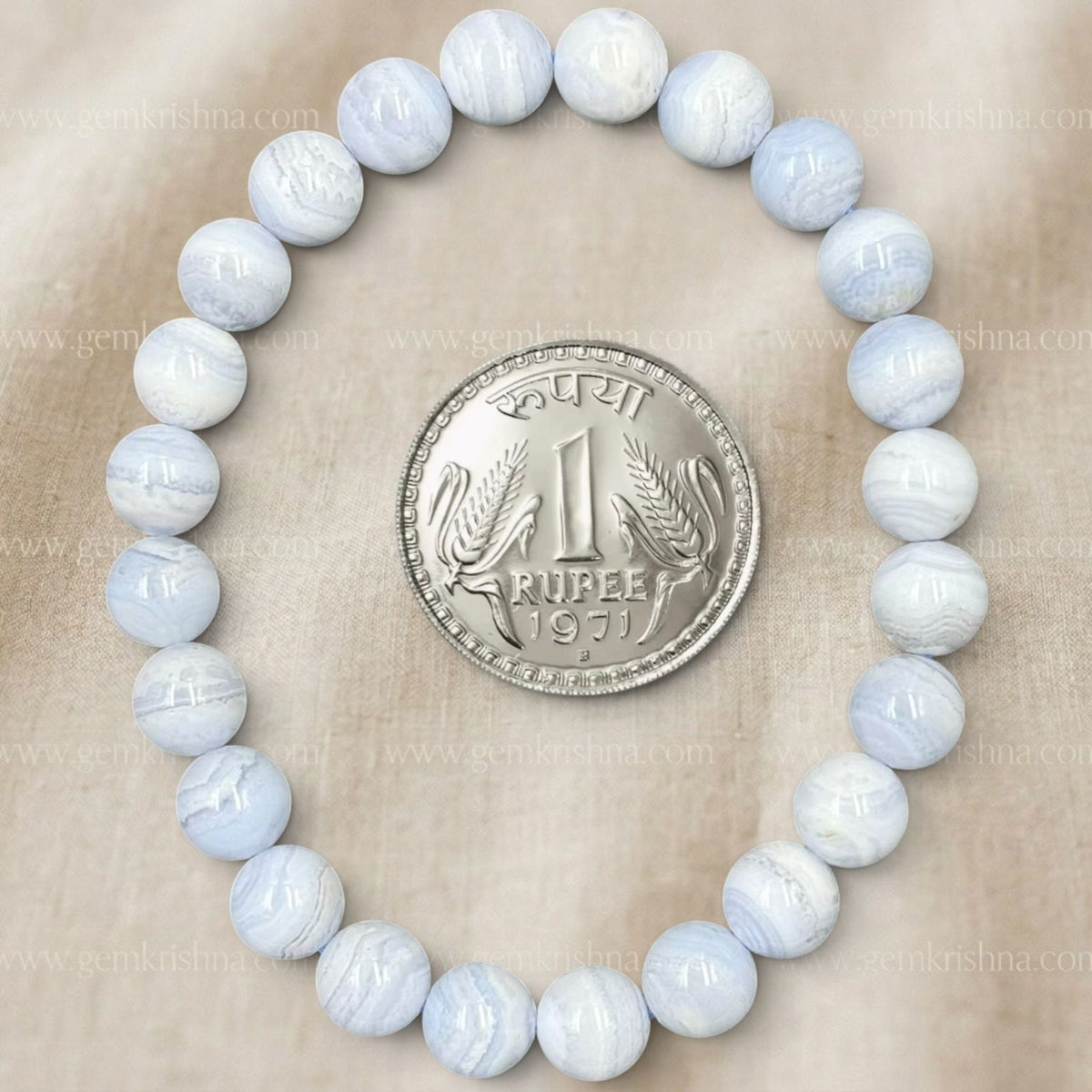 Blue lace agate bracelet showing variegated bead patterns with rupee coin on beige surface