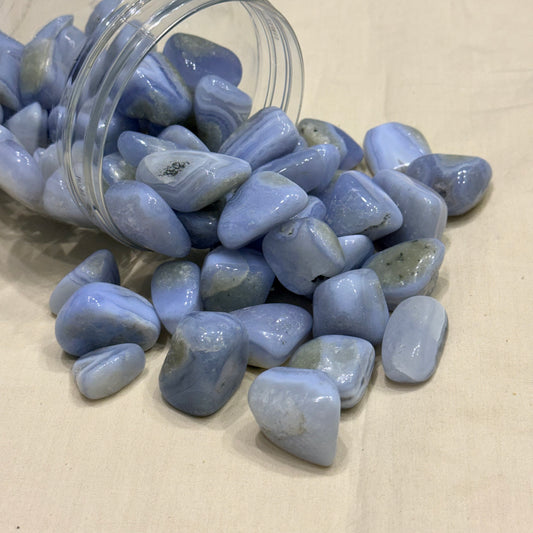 Blue lace agate tumble stones scattered in a glass jar, smooth polished stones
