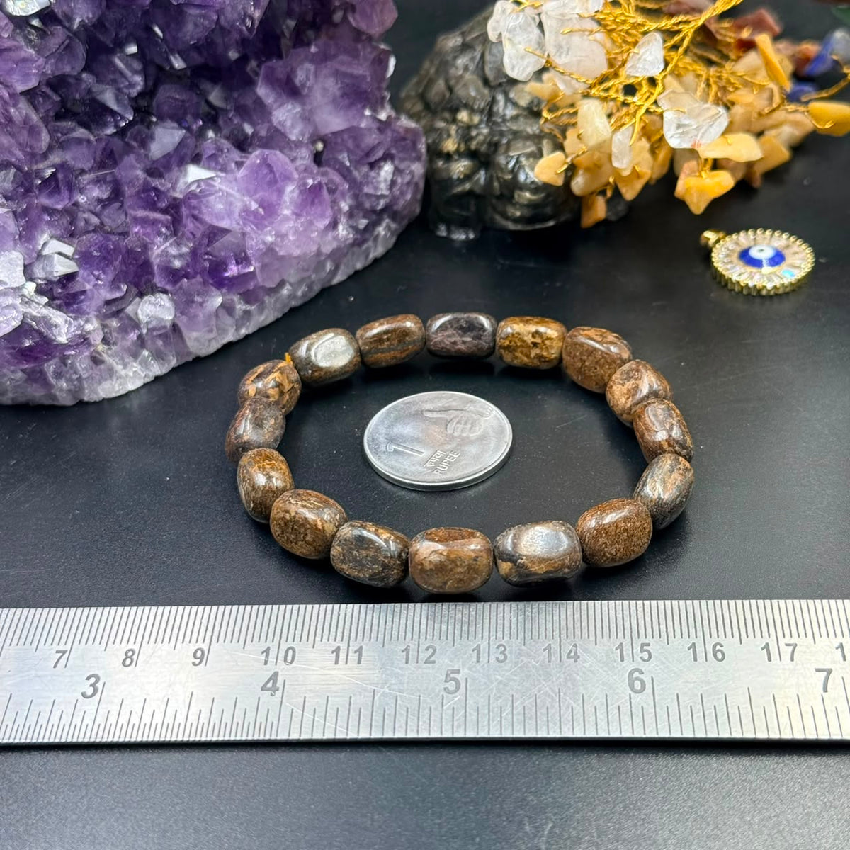 Bronzite tumble bracelet with round beads against amethyst crystal and ruler