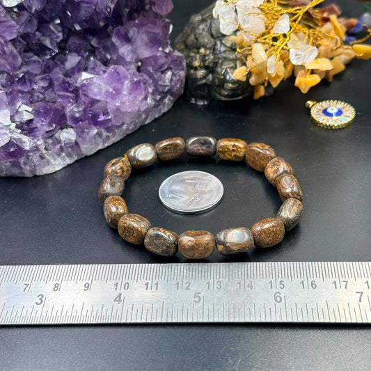 Bronzite tumble bracelet with round beads against amethyst crystal and ruler