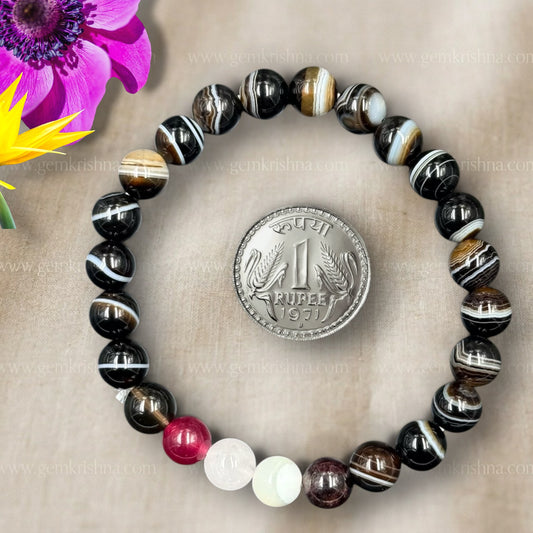 Capricorn bracelet laid on fabric with beaded stones and a coin medallion