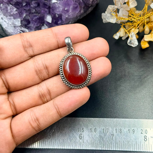 Carnelian 925 silver locket pendant front view with round red stone set in beaded frame in hand