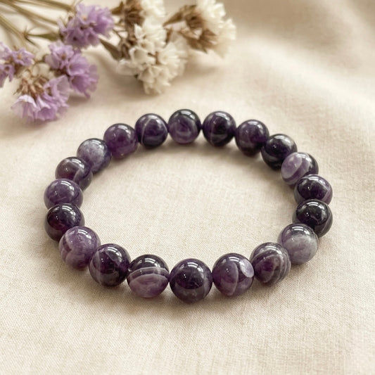 Chevron amethyst beaded bracelet in a curved circle on light fabric with purple dried flowers