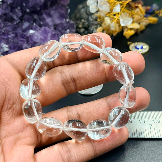 Clear quartz sphatik tumble bracelet held in hand showing smooth oval crystal beads
