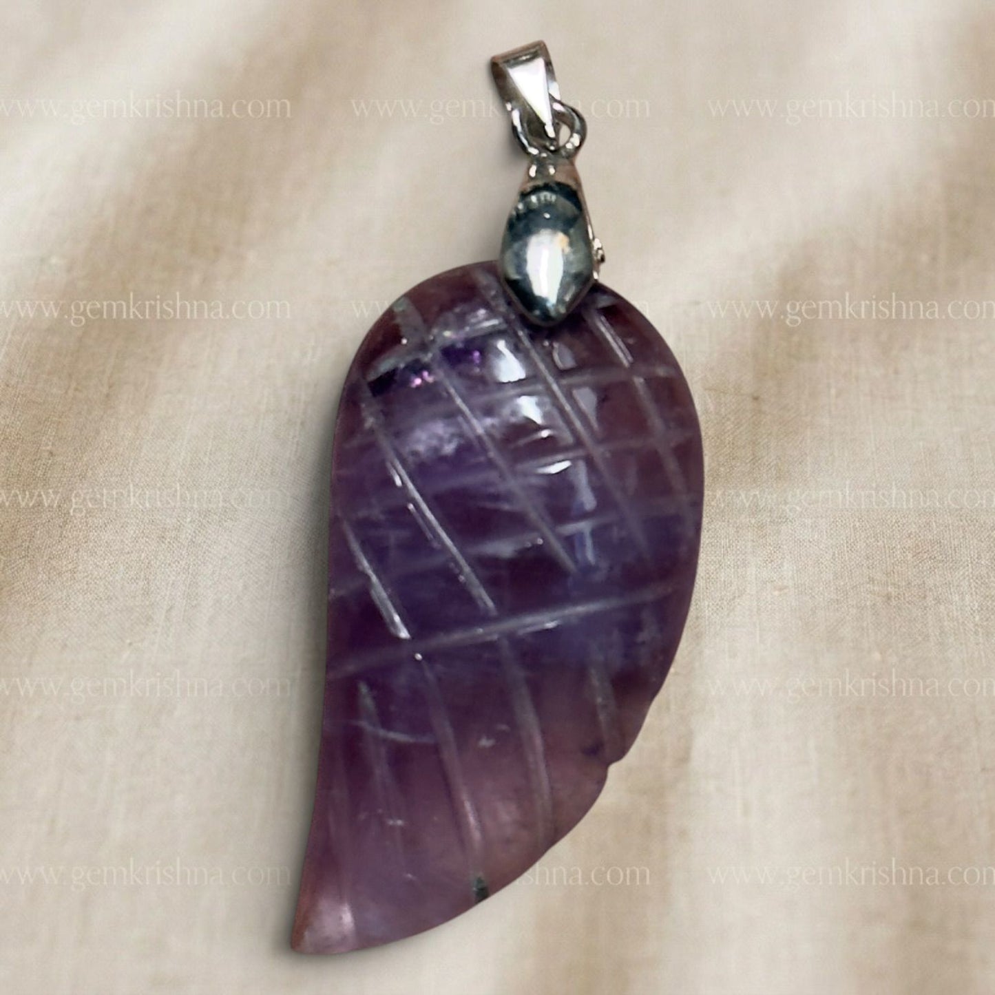 Close-up of amethyst wing feather locket pendant with silver-tone bail, on light background
