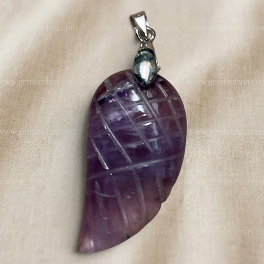 Close-up of amethyst wing feather locket pendant with silver-tone bail, on light background