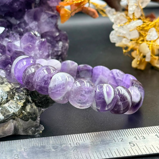 Close-up of chevron amethyst bracelet beads in shades of lavender and white on a ruler