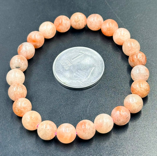 Natural Pink Aventurine Bracelet with round beads next to a 1 Rupee coin on black surface