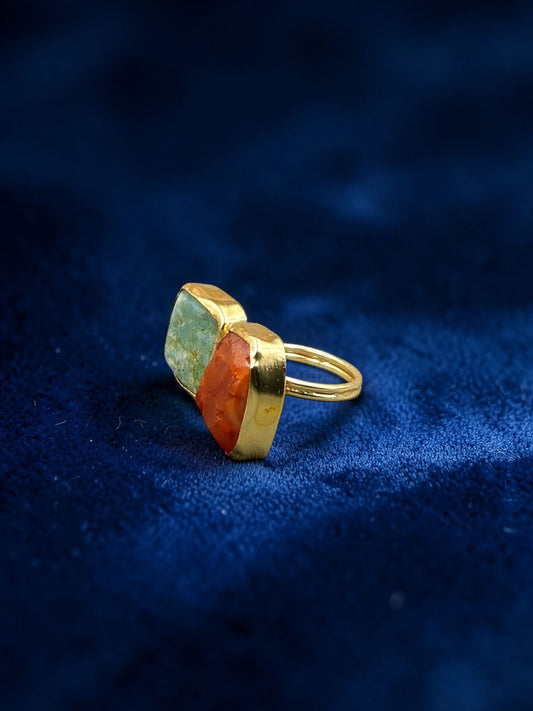 Green aventurine and carnelian rough metal ring on blue velvet fabric, side view