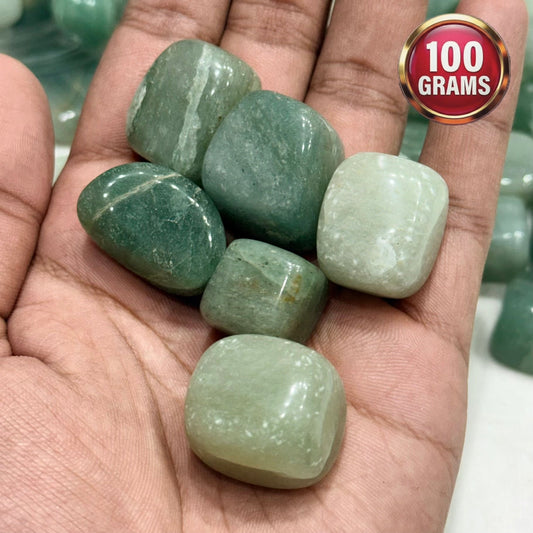Green aventurine tumbled stones in an open palm with a 100 grams label