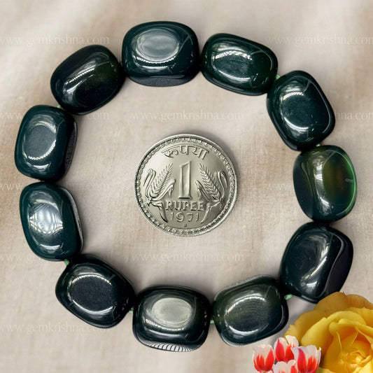 Green jade tumble bracelet beads arranged in a circle with rupee coin for size