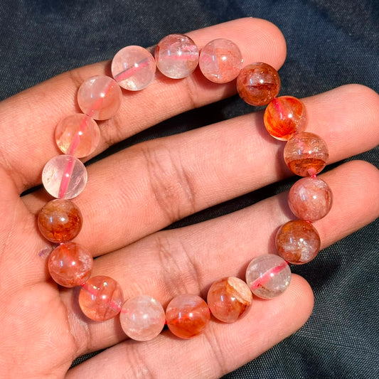 Hematoid quartz lepidocrocite bracelet with pink and orange beads in hand view