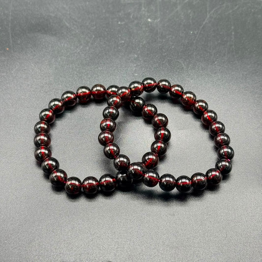 Hessonite Garnet (Gomed) stretch bracelet showing deep reddish-brown 8mm polished round beads on gray surface