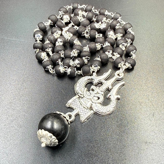 Karungali bead mala with Om Trishul metal pendant laid on grey background with bead links