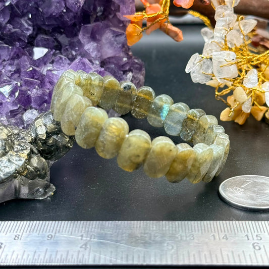 Labradorite oval flat bead bracelet close-up with purple crystal backdrop and measuring tape