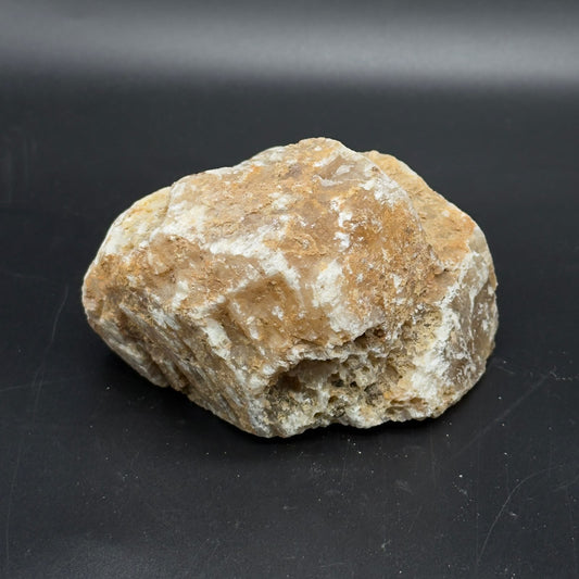 Large rough golden calcite crystal close-up on dark gray surface