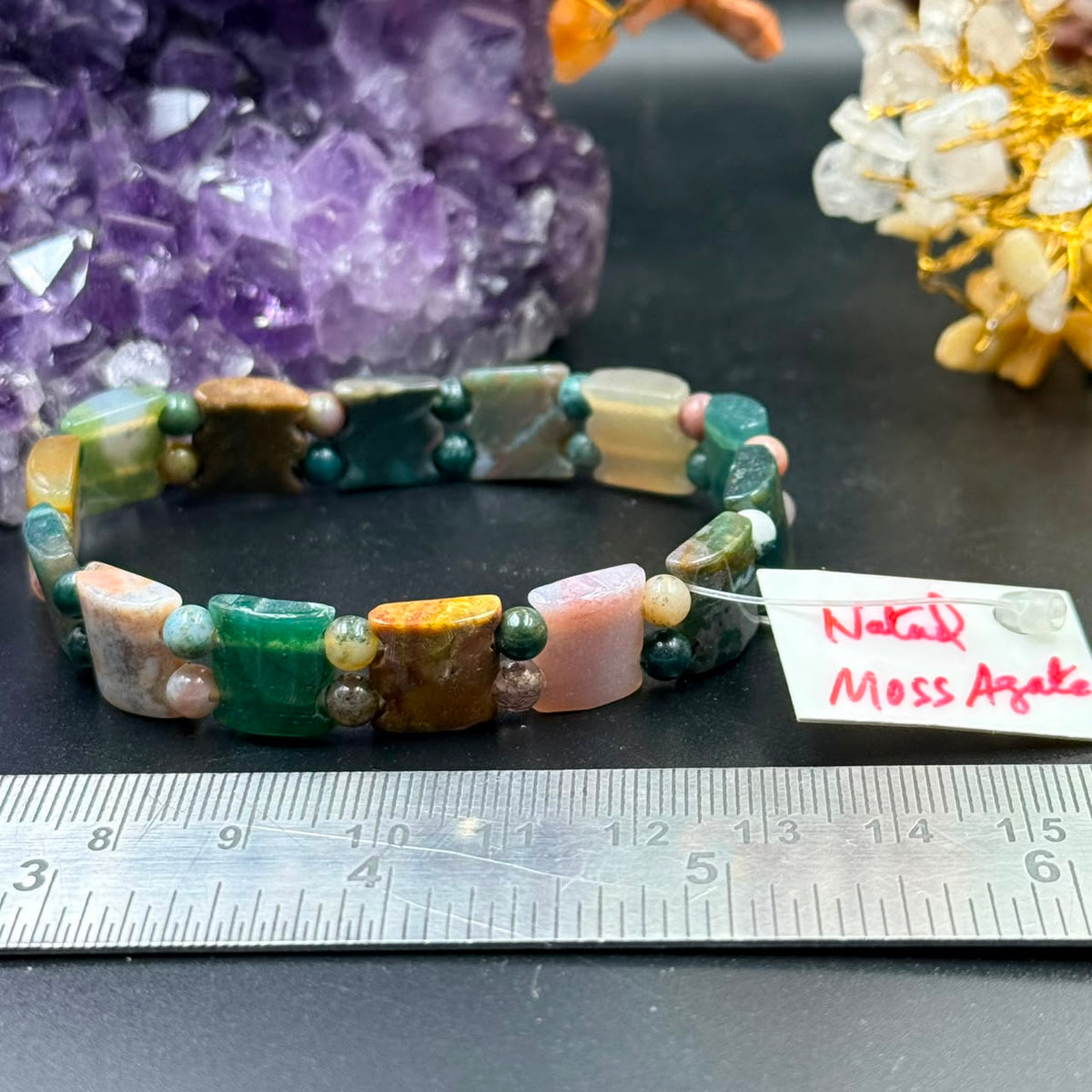 Moss agate bow-tie bead bracelet close-up with gemstone beads and labeled card on tabletop