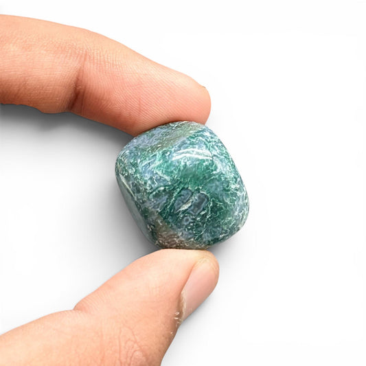 Natural moss agate tumble stone held in fingers with green mossy patterns