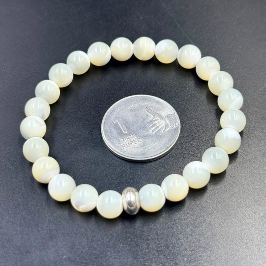 Mother of Pearl bracelet beads with silver spacer, shown on dark blue textured background