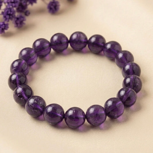 Natural amethyst bracelet showing glossy round purple beads on beige fabric