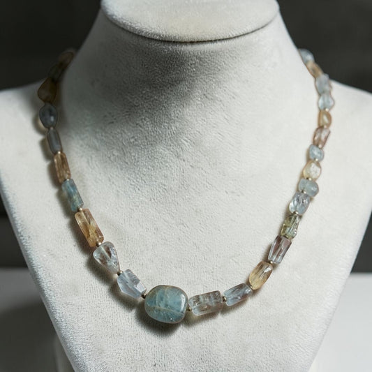 Natural aquamarine beaded necklace with oval aquamarine center stone on white jewelry display
