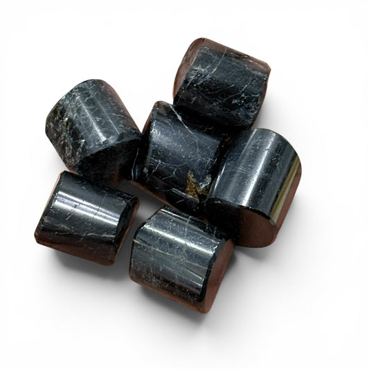 Natural black tourmaline tumble stones arranged on white background, close-up view