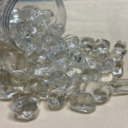 Natural clear quartz tumble stones scattered in a jar with a few pieces in view