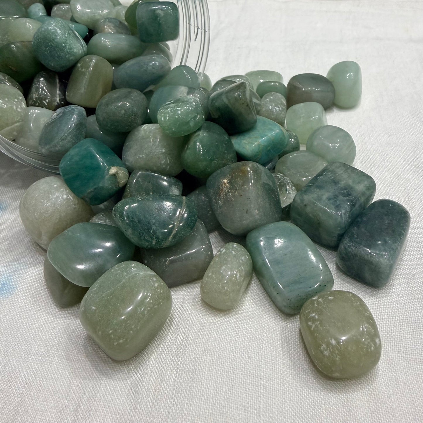 Natural green aventurine tumbled stones in a clear plastic bag, mixed sizes
