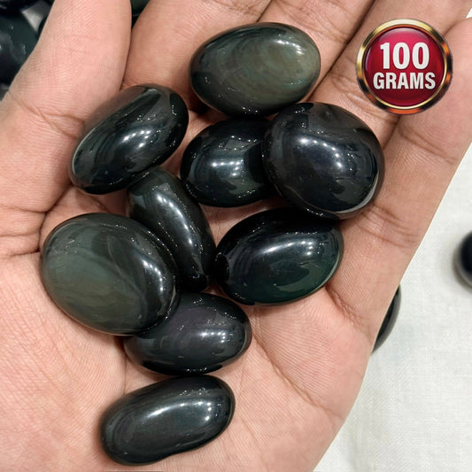 Rainbow obsidian tumble stones held in hand, glossy natural protection gemstones