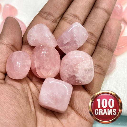 Natural rose quartz tumble stones held in an open palm, pink polished crystals