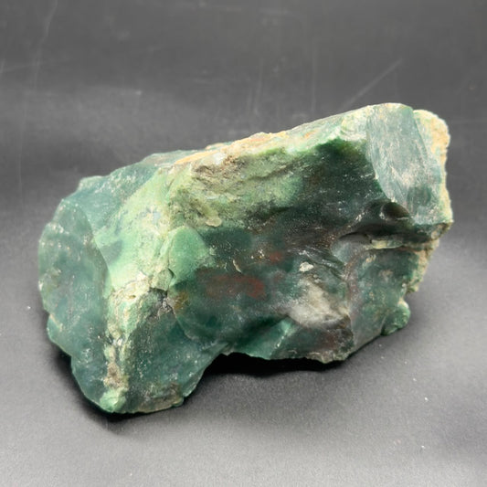 Natural rough bloodstone stone slab in green tones with dark speckles on gray background