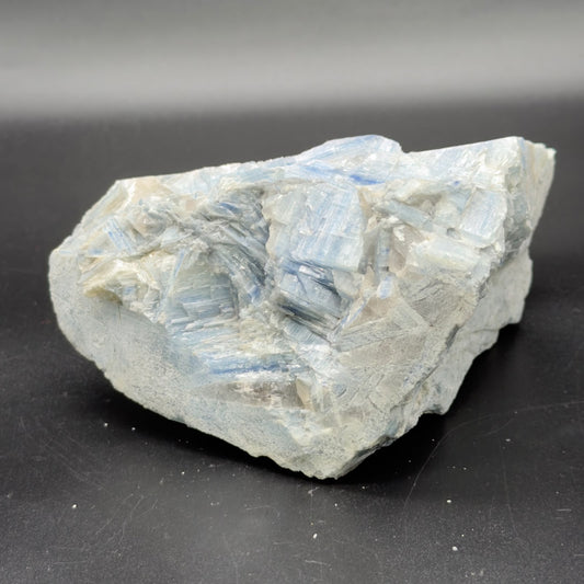 Natural rough blue kyanite crystal cluster close-up on dark surface