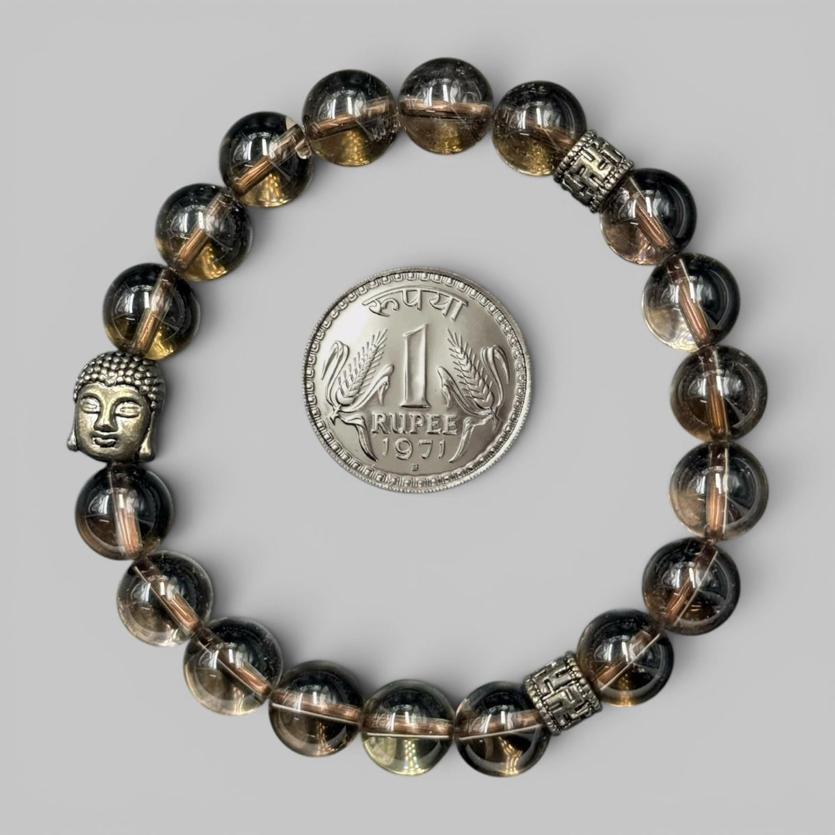 Natural Smoky Quartz Bracelet with silver Buddha and patterned metal beads next to 1 rupee coin