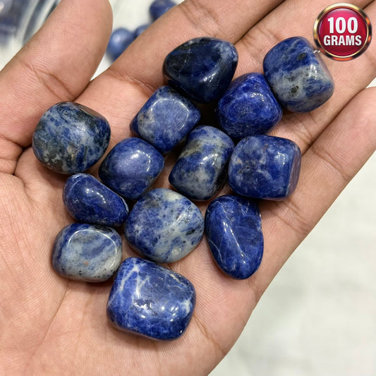 Natural sodalite tumble stones held in a hand, blue and speckled polished rock