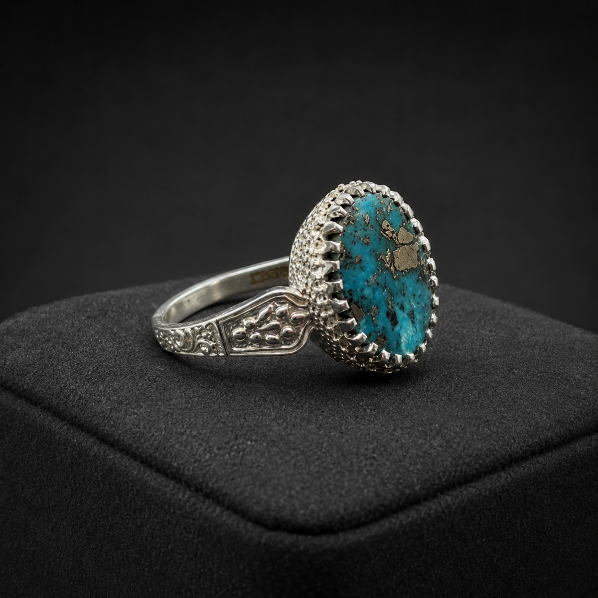 Oval turquoise filigree ring with ornate side details on black jewelry display