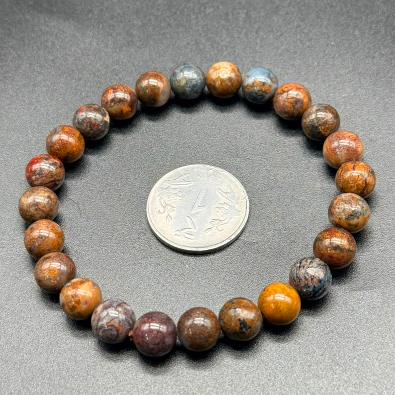 Pietersite bracelet with round gemstone beads shown beside a coin for scale
