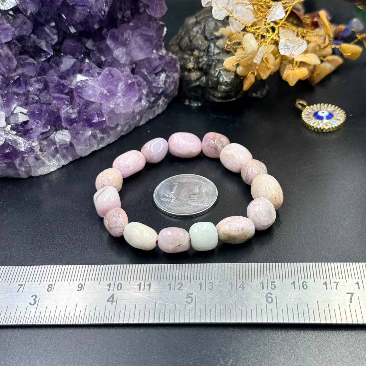 Pink Kunzite tumble bracelet with mixed pastel beads, laid flat on dark surface by ruler