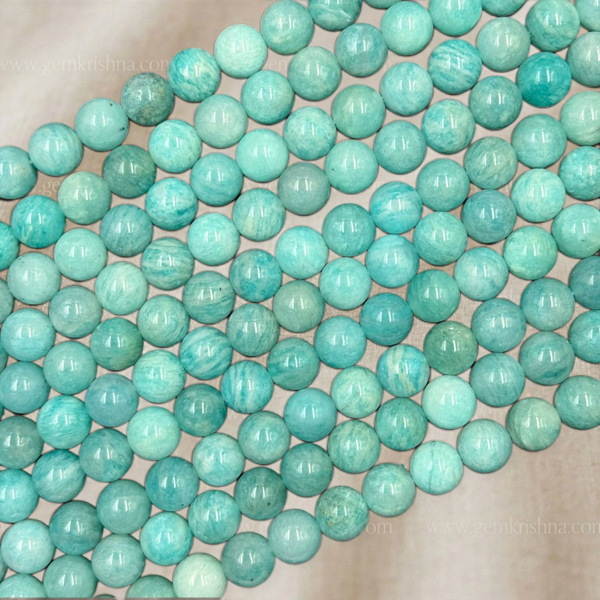 Polished amazonite round beads with glossy mint-blue color arranged on light background