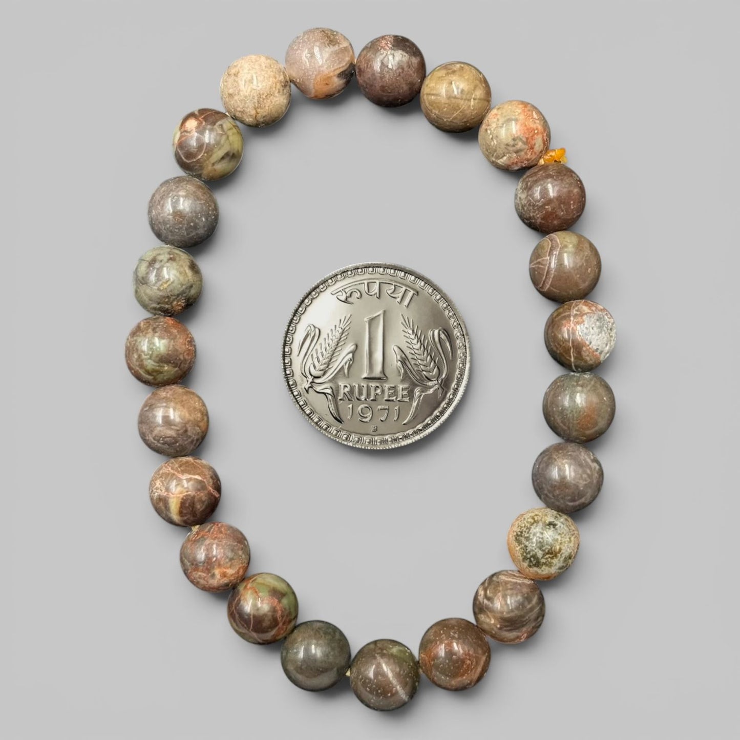 Polychrome jasper bracelet beads shown with coin size reference on gray background