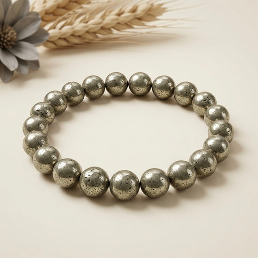 Pyrite bracelet with round metallic beads arranged in a circle on a cream background