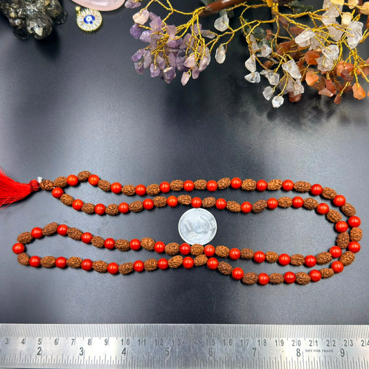 Red coral bead and rudraksha jap mala strands with red tassel shown on measuring board