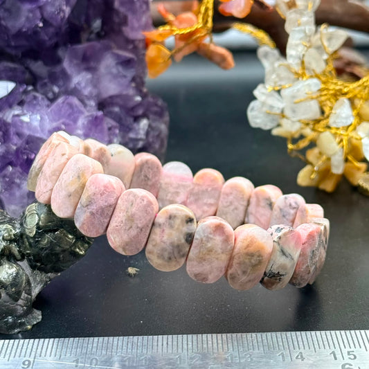 Rhodochrosite oval flat bead bracelet shown in close-up with pastel pink and rose beads on black surface