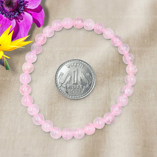Rose quartz bead bracelet with Rupee coin centerpiece and purple flower background